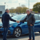Deux adultes serrant la main près d'une Peugeot 308 bleue