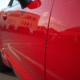 Voiture rouge brillante avec une rayure visible sur la porte